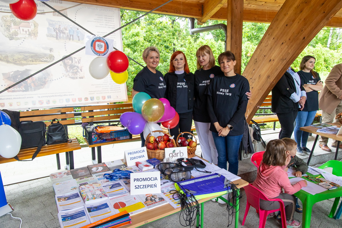 Stanowisko wystawiennicze, na stole podpis: promocja zdrowia, Promocja szczepień. Cztery kobiety w czarnych podkoszulkach z napisami PSSE NOWY Targ