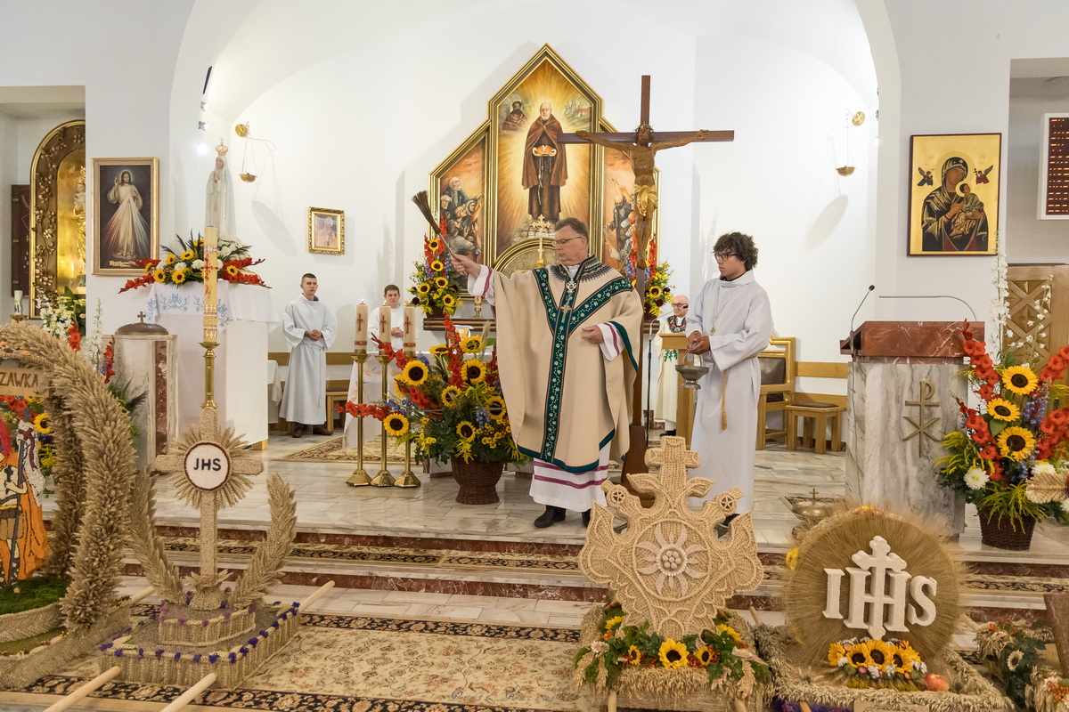 Ksiądz święci wieńce dożynkowe.