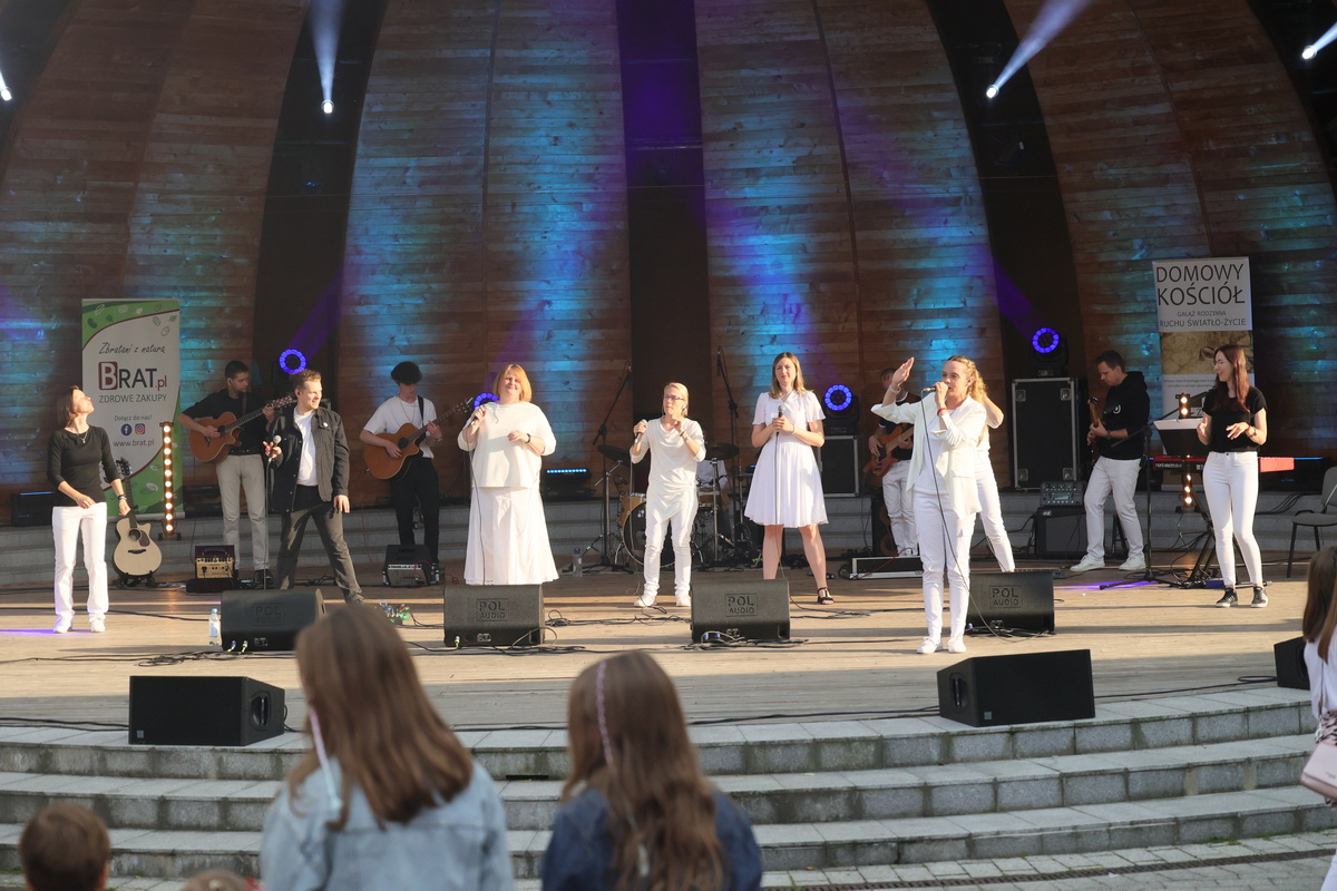 Zespół Mocni w Duchu - Kilkunastu wykonawców w biało-czarnych strojach: grają, śpiewają i tańczą.