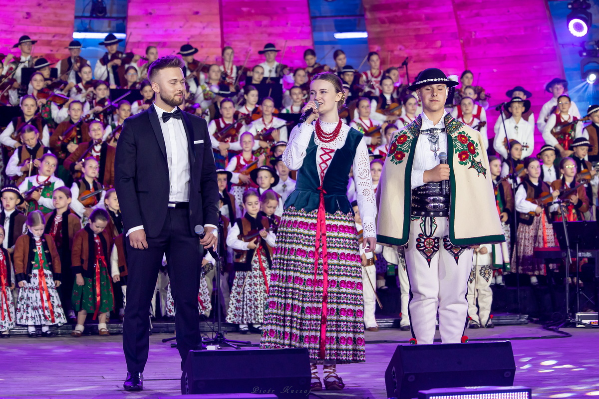 Soliści podczas koncertu, młody mężczyzna w smokingu,, góralka i góral.