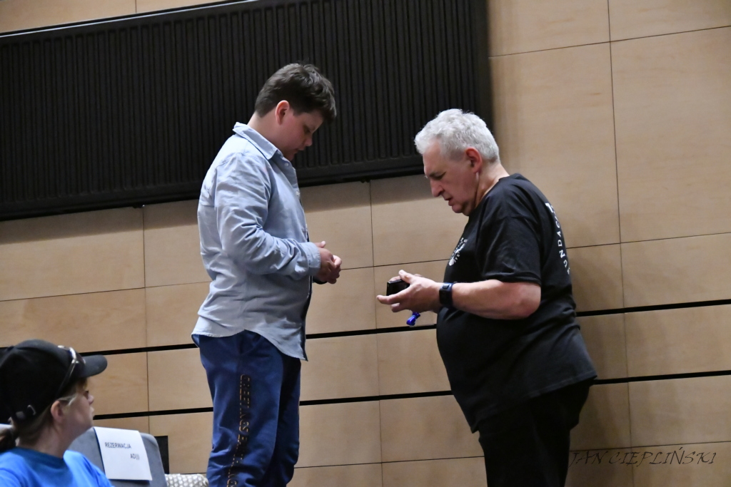 Pan daje chłopcu zestaw do słuchania audiodeskrypcji.