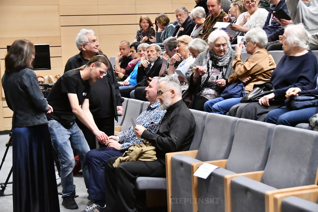 Pracownik teatru podaje niewidomemu mężczyźnie słuchawki.