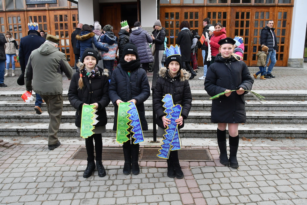 Harcerki stoją przed wejściem do kościoła i rozdają uczestnikom korony.