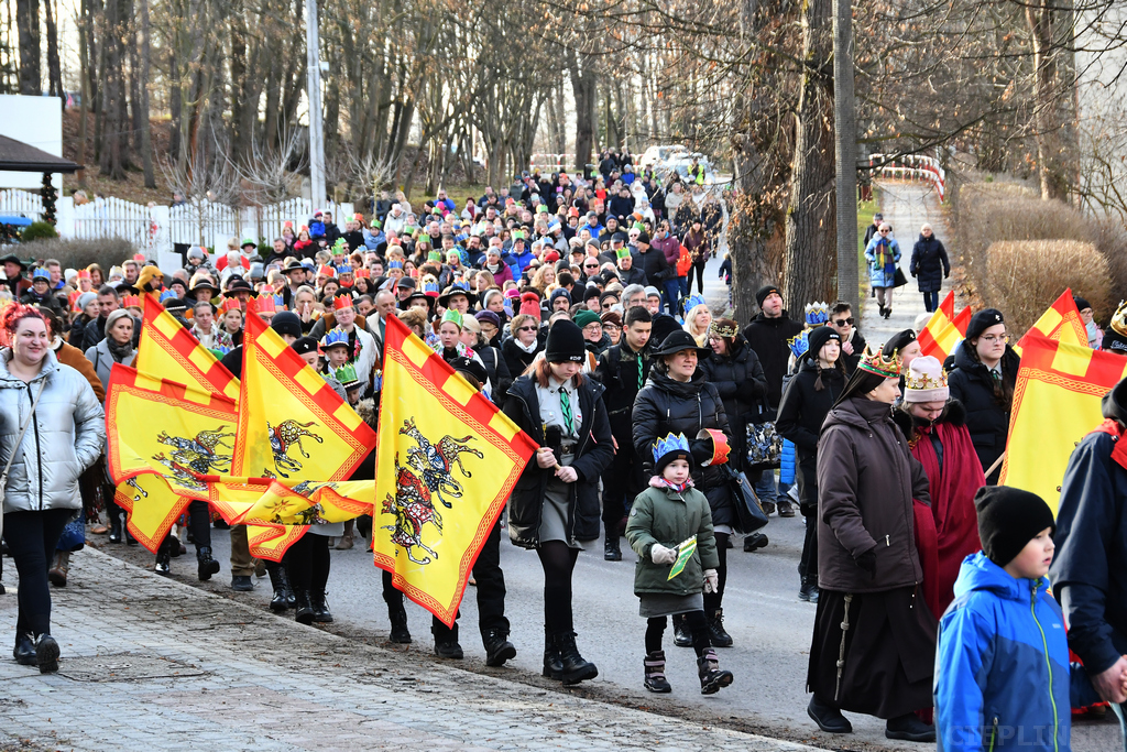 Pochód orszaku, na pierwszym planie harcerze niosą kolorowe flagi.