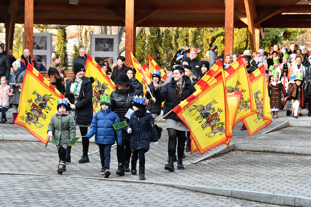 Na czele orszaku harcerze niosą wiele kolorowych flag.